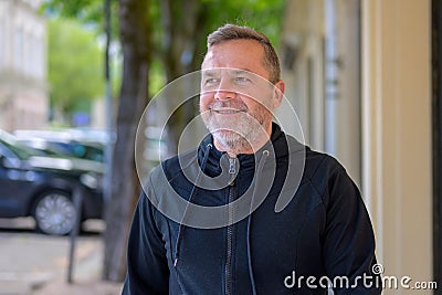 Middle-aged man chuckling to himself as he walks through town Stock Photo