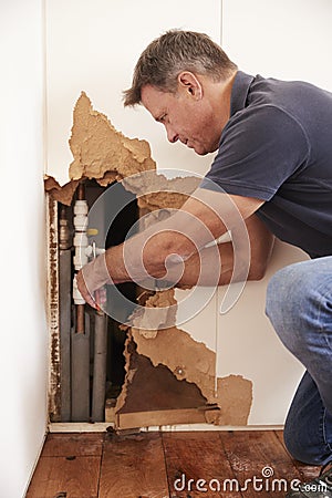 Middle aged man repairing burst water pipe, vertical Stock Photo