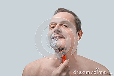 Middle aged man shaves with a razor. Portrait Of Handsome Man Shaving His Face Stock Photo