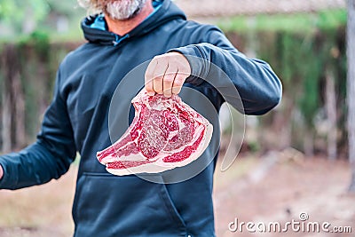 Middle-aged man shows a large beef steak Stock Photo