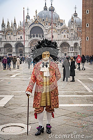 A middle-aged man in a vintage costume with a lace collar, wearing a carnival mask bordered by a circle of high black feathers, Editorial Stock Photo