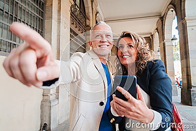 A middle aged mature couple pointing and watching the location on a gps app using a cellphone on a romantic journey trip Stock Photo