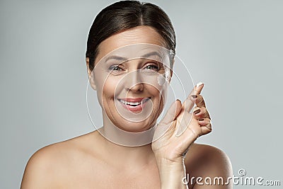 Middle aged woman applying anti-aging cream on her face Stock Photo