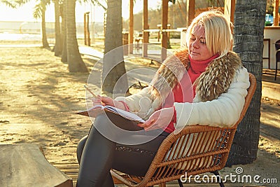 A middle-aged woman with blonde hair sits in a street cafe. Stock Photo