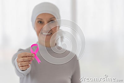 Middle-aged woman cancer patient lost hair from chemo cure process and use clothe cover her head holding pink ribbon the symbol of Stock Photo