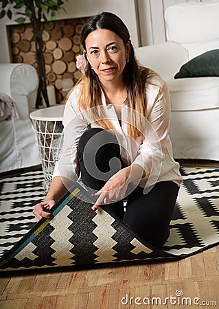 A middle-aged woman cleans up the room and lifted the edge of th Stock Photo