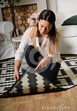 A middle-aged woman cleans up the room and lifted the edge of th Stock Photo