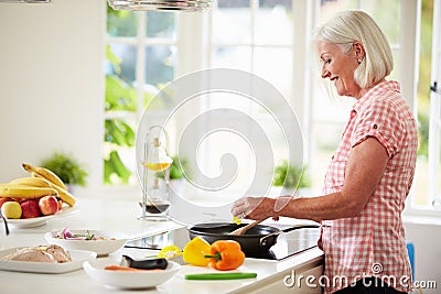 Middle Aged Woman Cooking Meal In Kitchen Stock Photo