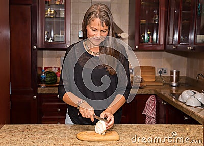 Middle aged woman cutting a white onion. Stock Photo