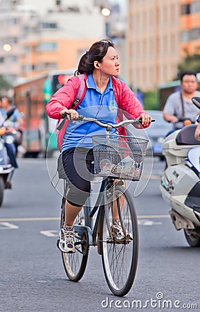 Middle-aged woman cycles in city center, Kunming, China Editorial Stock Photo