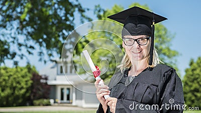 Middle aged woman with diploma in hand. Wearing a graduate uniform Stock Photo