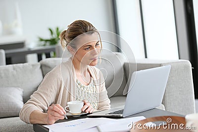 Middle-aged woman drinking coffee and working at home Stock Photo