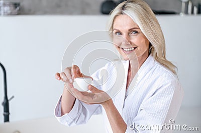 Middle aged woman hold jar with natural nourishing cream and smile Stock Photo