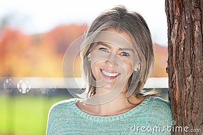 Middle aged woman leaning on tree Stock Photo