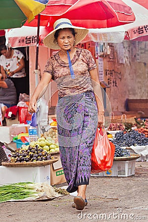 Middle-aged woman leaves a traditional market in Ruili, Yunnan Province, China Editorial Stock Photo