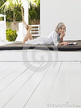 Middle Aged Woman Lying On Daybed On Verandah Stock Photo