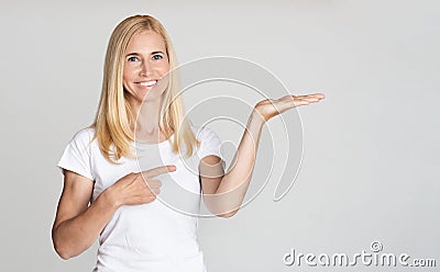 Middle aged woman presenting product on palm Stock Photo