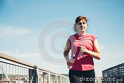 Middle aged woman running with water bottle Stock Photo