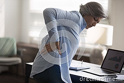 Middle-aged woman touch lower back, suffer from sudden backache Stock Photo