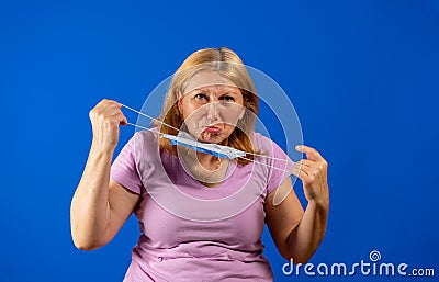 Middle blonde woman taking off her medical mask isolated on blue background Stock Photo