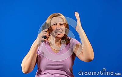 Middle blonde woman talking on smartphone over blue isolated background stressed with hand on head, shocked with shame Stock Photo