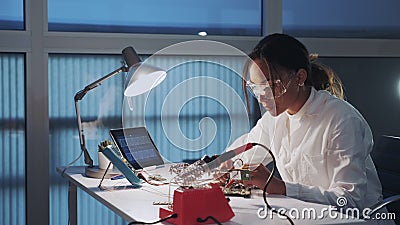 Middle close up of african american electronics engineer in protective glasses checking motherboard with multimeter Stock Photo
