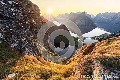 Radiant glow from the midnight sun over moss-covered rocks and dramatic peaks in Lofoten Stock Photo