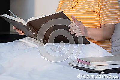 Midsection of adult obese woman is reading textbook on her bed in morning time Stock Photo