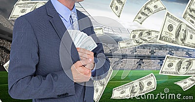 Midsection of businessman hiding money in blazer at football stadium representing corruption Stock Photo