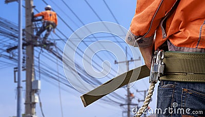 Midsection of electrician lineman wearing safety belt with blurred background of electrical workers team are working on power pole Stock Photo