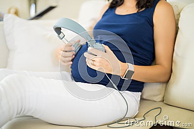 Midsection Of Expectant Mother Playing Music For Fetus Stock Photo
