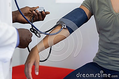 Midsection of frican american male doctor measuring blood pressure of biracial female patient Stock Photo