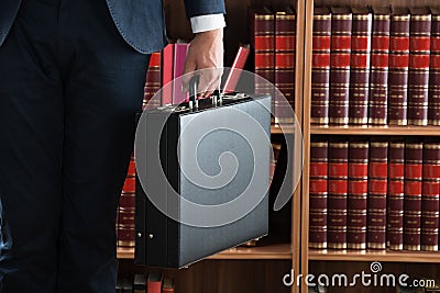 Lawyer Carrying Briefcase Against Bookshelf Stock Photo