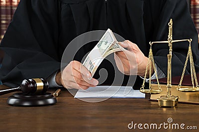 Corrupt Judge Holding Dollar Bundle At Desk Stock Photo