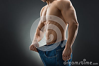 Midsection Of Muscular Man In Old Jeans Showing Weight Loss Stock Photo