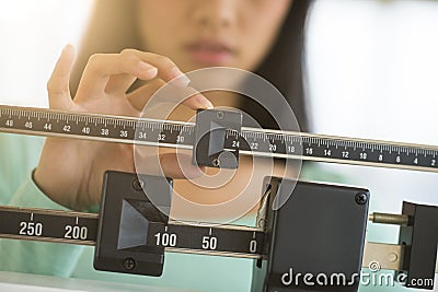 Midsection Of Woman Adjusting Weight Scale Stock Photo