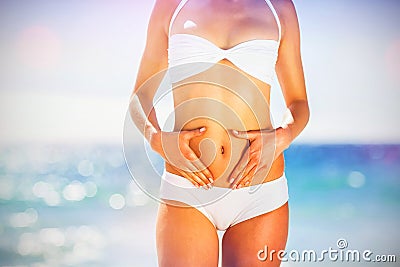 Midsection of woman in bikini touching her belly Stock Photo