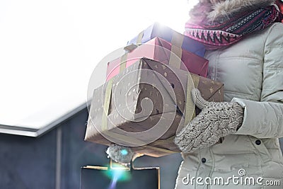 Midsection of woman carrying stacked gifts during winter by window Stock Photo