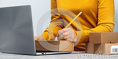 Midsection of a woman writing on a cardboard box. despatch Stock Photo