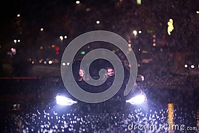 In the midst of a nighttime journey, a happy family enjoys playful moments inside a car as they travel through rainy Stock Photo