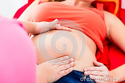 Midwife exanimating belly of pregnant woman manually Stock Photo