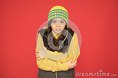 It might be too cold to trek outside. Little child feel cold red background. Small girl shiver in cold weather wear Stock Photo