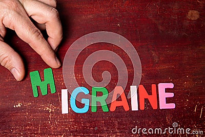 MIGRAINE. Overload and fatigue Concept. Text on painted wood background Stock Photo