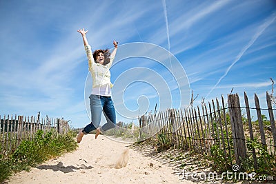 Miidle aged woman jumping on the beach Stock Photo