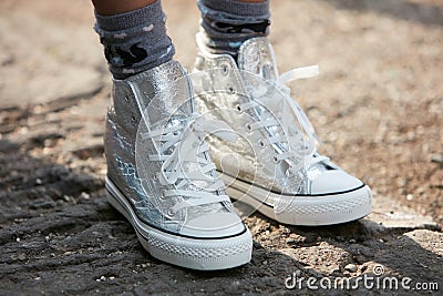 Woman poses for photographers with silver sneakers shoes before Emporio Armani fashion show, Milan Fashion Editorial Stock Photo