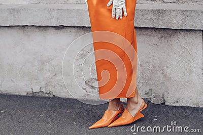 Elegant woman wearing orange long dress, black bag and white gloves Editorial Stock Photo