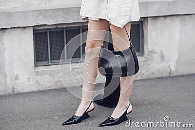 Street style, woman wearing cream leather jacket, mini skirt with long train, black Prada bag and Prada heels Editorial Stock Photo