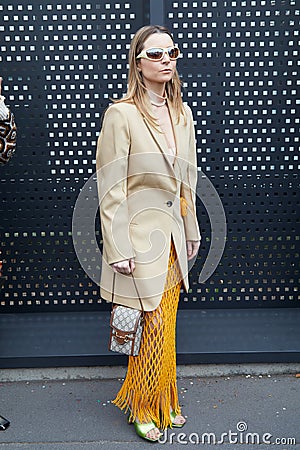 MILAN, ITALY - FEBRUARY 24, 2023: Woman with beige jacket, Gucci bag and orange net skirt before Gucci fashion show, Milan Fashion Editorial Stock Photo