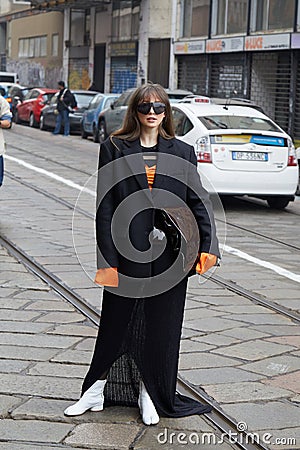 MILAN, ITALY - FEBRUARY 24, 2023: Woman with black jacket and orange shirt before Sportmax fashion show, Milan Fashion Week street Editorial Stock Photo