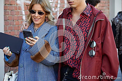 Woman and man with red and blue Fendi logo shirt walking before Fendi fashion show, Milan Fashion Editorial Stock Photo